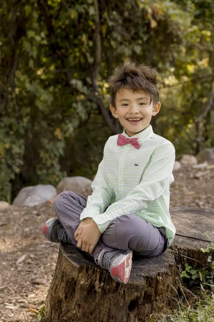 2nd grade boy sitting on tree stump