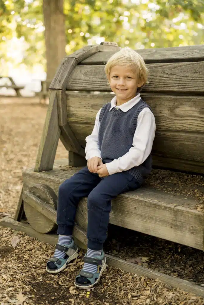 Preschool boy sitting on playground equipment